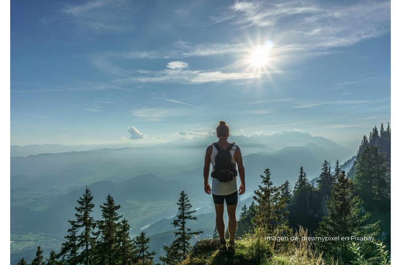 Imagen persona en una montaña con sol de fondo