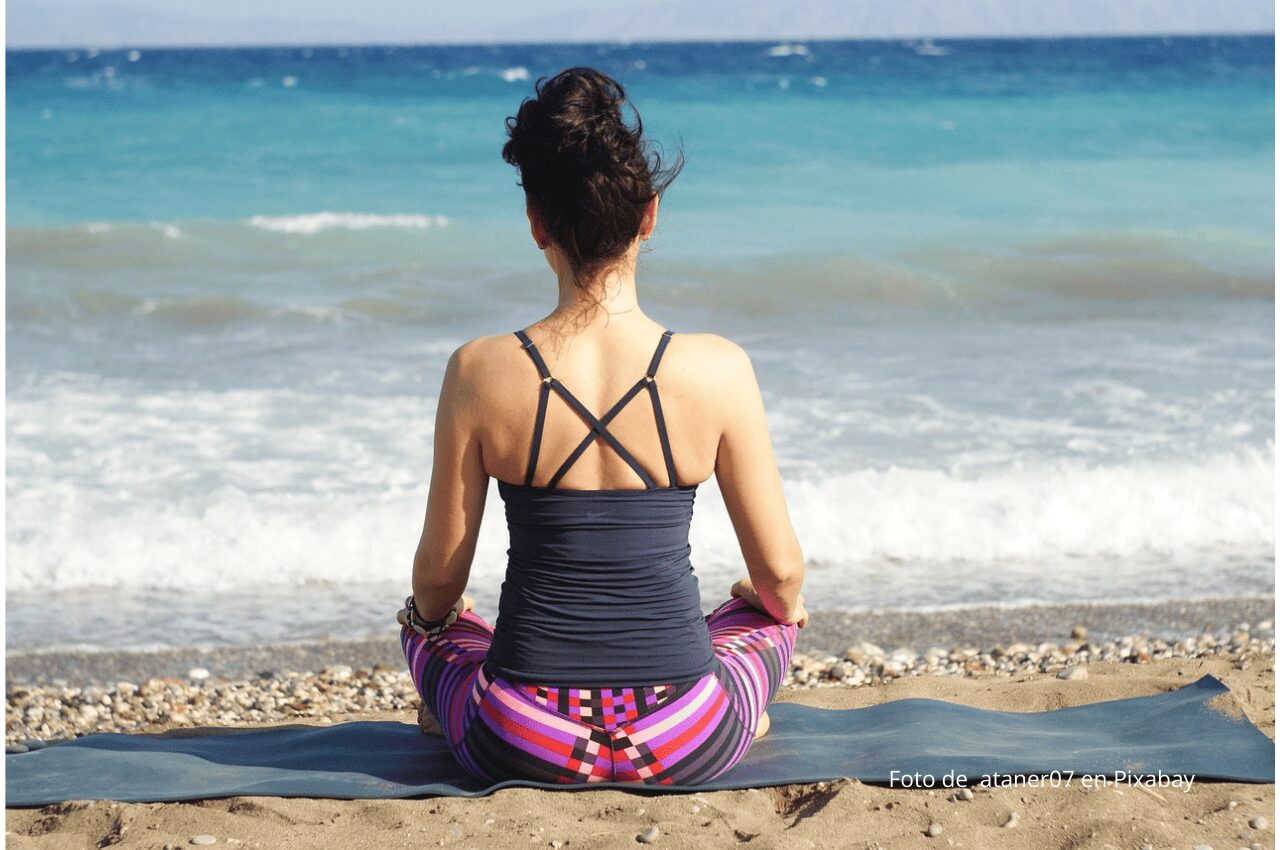 Imagen chica meditando de espaldas junto al mar