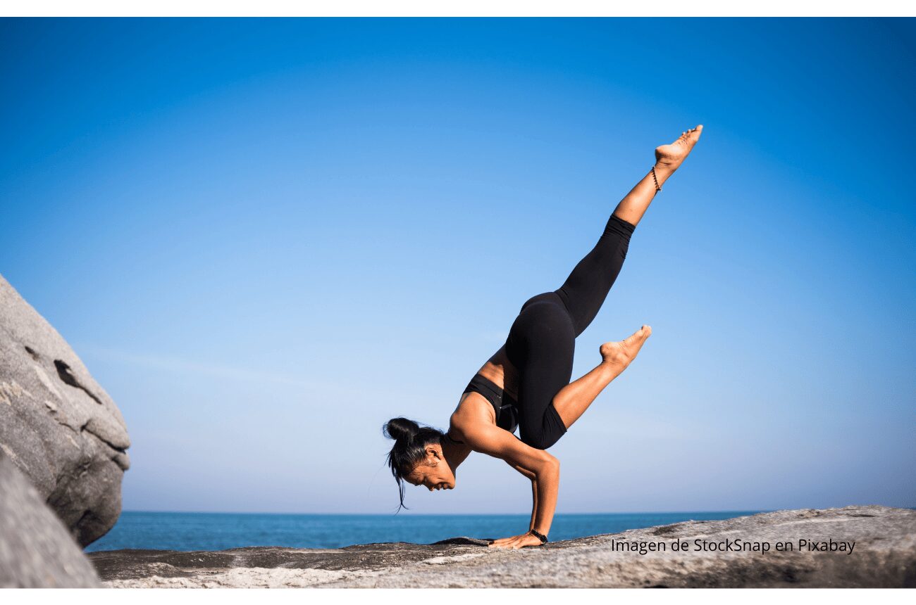 Imagen chica haciendo yoga en roca con cielo azul
