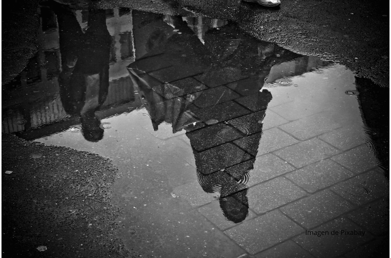 Imagen de reflejo de dos personas en un charco en el suelo